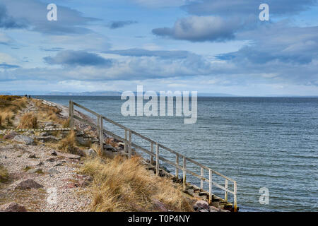 FINDHORN BEACH Moray Firth Scozia gradini in legno che conduce nel mare il Black Isle oltre e neve sulle montagne Foto Stock