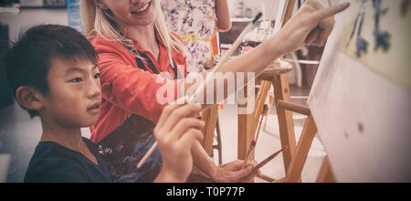 Insegnante assistere schoolboy nella classe di disegno Foto Stock