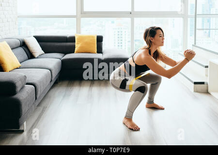 Donna adulta gambe di formazione facendo squat laterale a casa Foto Stock