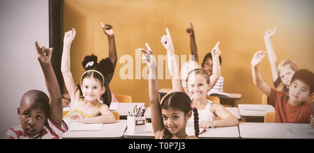 Gli studenti alzando le mani in aula Foto Stock