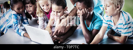 Insegnanti e bambini che utilizzano computer portatile in biblioteca Foto Stock