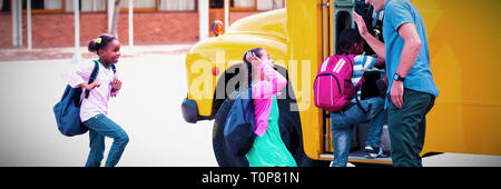 Docente dando alta cinque per i bambini mentre entrando in autobus Foto Stock