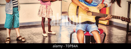 Insegnante assistendo a bambini e ragazzi per suonare uno strumento musicale in aula Foto Stock