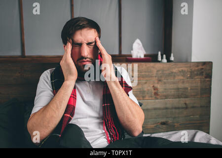 Immagine da un giovane con fazzoletto. Ragazzo malato si trova nel letto e ha naso che cola. uomo fa una cura per il raffreddore comune modello maschio ha una alta temper Foto Stock