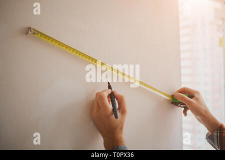 Il falegname con la matita in mano misura il tagliere un metro a nastro  sulla lavorazione del legno Foto stock - Alamy