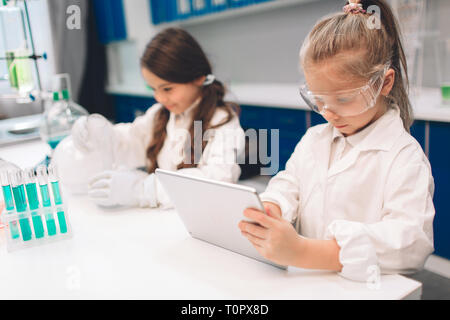 Due bambini piccoli in camice da laboratorio di chimica di apprendimento in laboratorio scolastico. Per i giovani scienziati degli occhiali di protezione rendendo esperimento in laboratorio o cabina di chimica Foto Stock