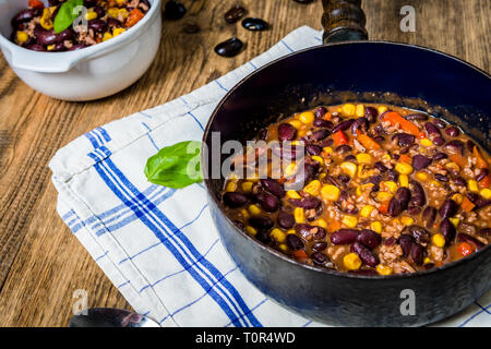 Chili o peperoncino carne di mais. Cucinati a fagiolo, carni macinate, peperoncino, mais e pepe in padella sulla tavola di legno Foto Stock
