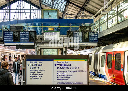 Le tavole indicatrici del treno blu d'epoca annunciano informazioni sui treni ai passeggeri alla stazione della metropolitana di Earls Court , Londra, Regno Unito Foto Stock