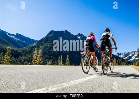 Una giovane coppia cavalcare le loro biciclette fino a Washington Pass nel North Cascades dello Stato di Washington, USA. Foto Stock