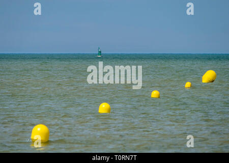 Boe di colore giallo e mini faro non lontano dalla spiaggia di mare Foto Stock