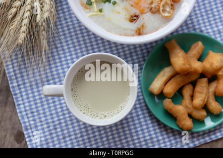 Breakfase pasto. Congee o riso porridge di carne macinata di maiale, uovo sodo con latte di soia e il cinese fritte doppio bastone di pasta Foto Stock