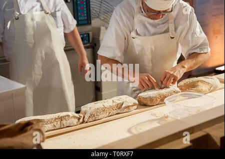 Il panettiere mettere focacce sulla buccia prima della cottura Foto Stock