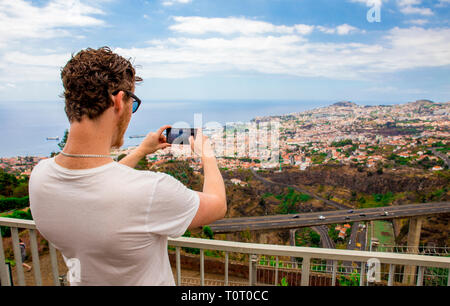 Giovane uomo turistica prendendo una foto della città di Funchal sull' isola di Madeira Portogallo, sul giorno d'estate. Foto Stock