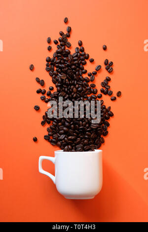 I chicchi di caffè in tazza di caffè sui coralli viventi dello sfondo. Il colore dell'anno 2019 concept. Disposizione verticale Foto Stock