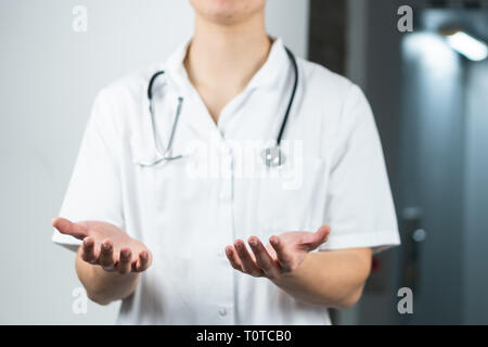 Luminose ravvicinata di un medico di sesso maschile in uniforme con uno stetoscopio aventi ampia mani aperte. Copia spazio o spazio grafico Foto Stock