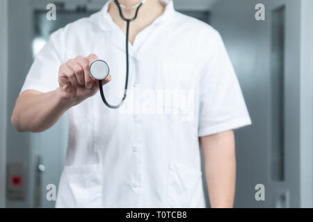 Luminose ravvicinata di un medico di sesso maschile in uniforme con uno stetoscopio. Ascolto e tenendo uno stetoscopio. Spazio di copia Foto Stock