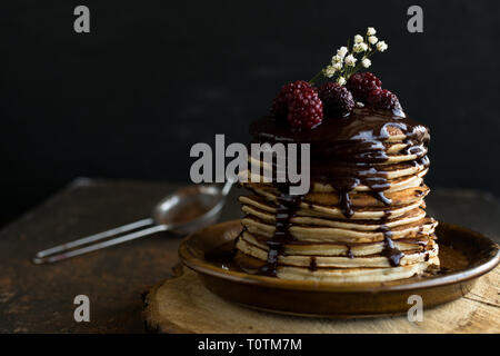 Pancake fatti in casa con i lamponi e il cioccolato su uno sfondo nero Foto Stock