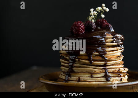 Pancake fatti in casa con i lamponi e il cioccolato su uno sfondo nero Foto Stock