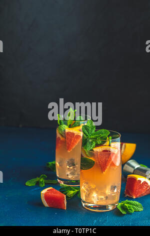 Pompelmo e menta il gin tonic cocktail, drink con ghiaccio. Estate a freddo di agrumi bevanda rinfrescante cocktail o bevande con ghiaccio sul blu scuro conc Foto Stock