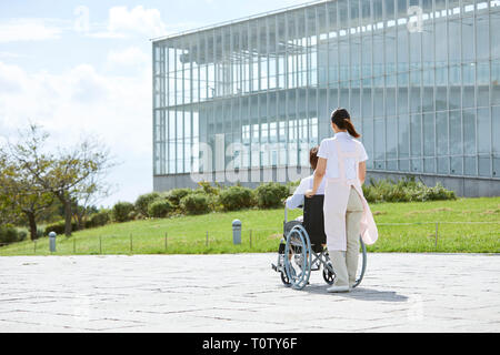 Un giovane giapponese operatore sanitario a prendersi cura del paziente anziano Foto Stock