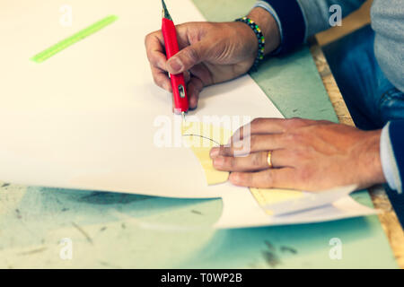 Calzolaio o scarpa designer che lavora con lcon libro modelli per taglio di pelle. Foto Stock