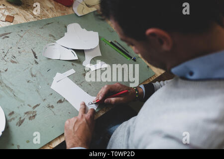 Calzolaio o scarpa designer che lavora con lcon libro modelli per taglio di pelle. Foto Stock