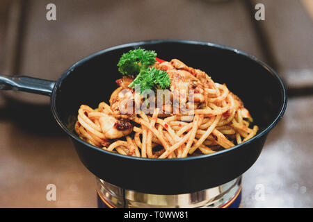 Spaghetti saltate in padella con funghi su un tavolo di legno Foto Stock