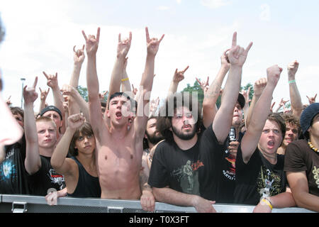 Fila anteriore heavy metal tifosi sono mostrati con le loro armi in aria durante un 'live' prestazioni di concerto. Foto Stock