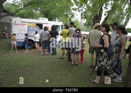 I frequentatori di concerti sono mostrati in attesa in linea per Mister Softee durante un outdoor festival di musica. Foto Stock