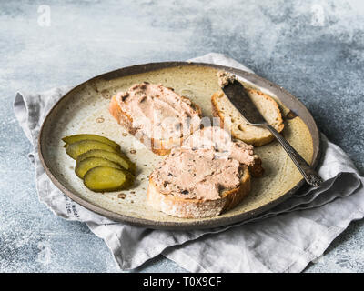 Due fette biscottate di anatra con prugne rillettes pate sul pane bianco con cetriolo sottaceto fette sulla piastra vintage Foto Stock