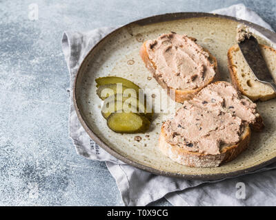 Due fette biscottate di anatra con prugne rillettes pate sul pane bianco con cetriolo sottaceto fette sulla piastra vintage Foto Stock