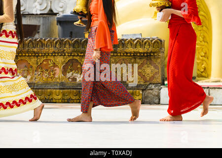 (Fuoco selettivo) Alcuni buddista birmano fedeli si cammina a piedi nudi intorno alla Shwedagon pagoda indossando un tradizionale e il longyi colorati. Foto Stock