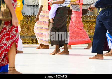 (Fuoco selettivo) Alcuni buddista birmano fedeli si cammina a piedi nudi intorno alla Shwedagon pagoda indossando un tradizionale e il longyi colorati. Foto Stock