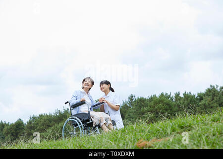 Custode giapponese aiutando paziente senior Foto Stock