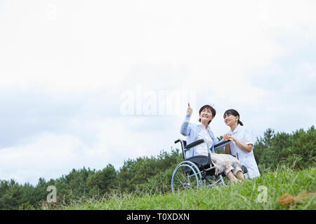 Custode giapponese aiutando paziente senior Foto Stock