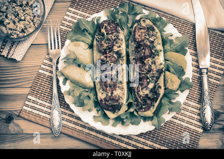 Zucchine su una piastra farcite con carne macinata e verdure con patate e insalata verde. Vista superiore Foto Stock