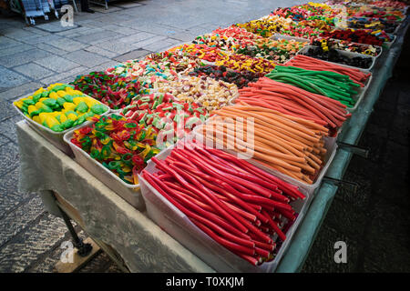 Varie gelatina colorata i dolciumi e la pasticceria esposta in scatole di plastica per la vendita in strada. Colori contrastanti di caramelle e matite dolce mettere f Foto Stock