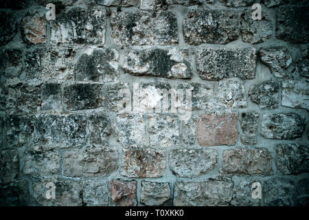 Background urbano, grigia rovinata antico muro in mattoni. Antica struttura in mattoni. Parte del vecchio edificio. I vecchi tempi. Storia e archeologia Foto Stock