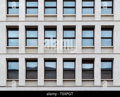 Close-up e modello di finestre con vetro blu sulla facciata di un moderno edificio in pietra, di consistenza Foto Stock