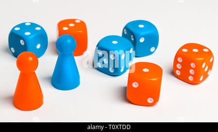 Un gruppo di blu e colorato di rosso il gioco d'azzardo dice con pedine di vari colori per la scheda giochi su un uniforme sfondo bianco Foto Stock