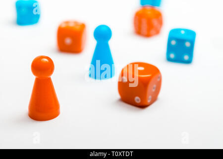 Un gruppo di blu e colorato di rosso il gioco d'azzardo dice con pedine di vari colori per la scheda giochi su un uniforme sfondo bianco Foto Stock