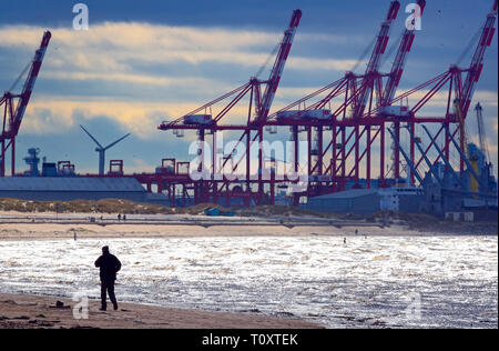 La gente camminare sotto il sole sulla spiaggia Crosby nel Merseyside a fianco di Anthony Gormley "un altro luogo' uomini di ferro sculture. Foto Stock