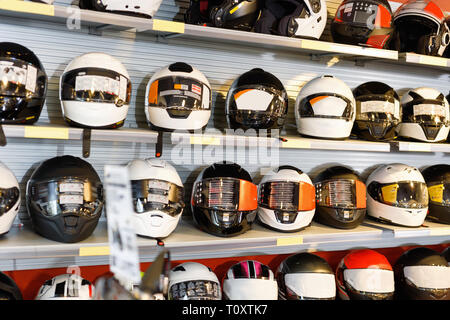 Interno di un elegante salone di moto con colorati caschi moto sui ripiani Foto Stock