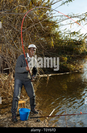 Emotional ritratto di uomo africano tirando con asta di pescare sul fiume Foto Stock