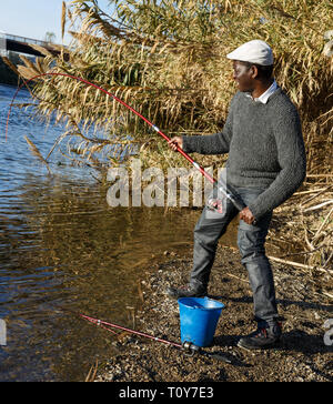 Emotional ritratto di uomo africano tirando con asta di pescare sul fiume Foto Stock