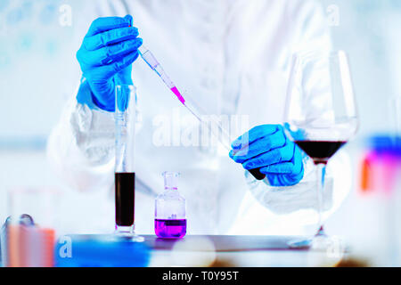 Il controllo di qualità esperto di ispezionare il vino rosso in laboratorio Foto Stock