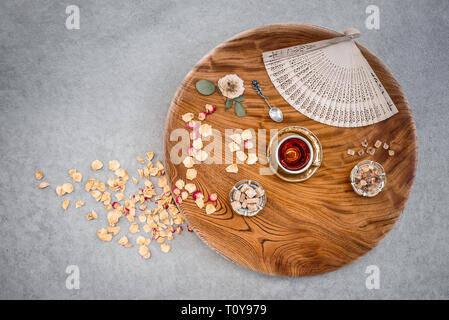 Tè e zucchero su un giro di tavolo in legno decorato con petali di rosa e la ventola. Foto Stock