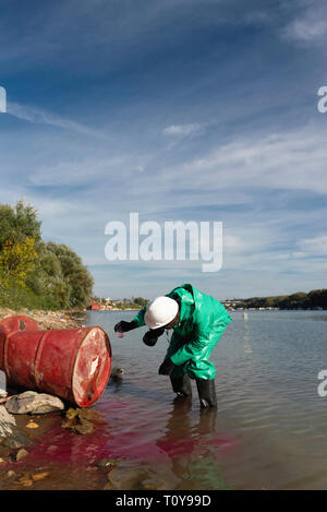 Controllo dell inquinamento ufficiale in tuta protettiva del prelievo dei campioni di sostanza tossica che perde dal tamburo Foto Stock