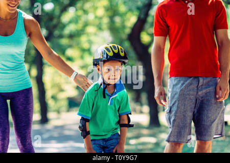 Famiglia con un bambino di pattinaggio nel parco. Foto Stock