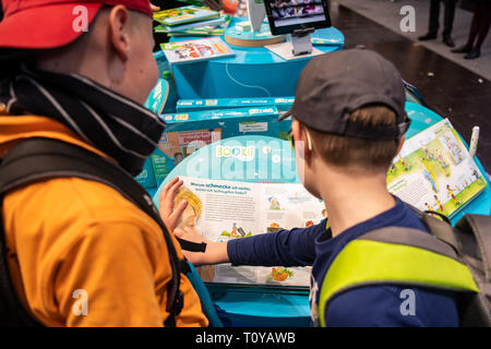 Leipzig, Germania. Xxi Mar, 2019. I visitatori di leggere un libro presso lo stand di BOOKii durante il 2019 Lipsia Fiera del Libro di Lipsia, Germania, 21 marzo 2019. Quattro giorni di Leipzig Book Fair ha dato dei calci a fuori di giovedì, che attrae oltre 2.500 espositori provenienti da più di cinquanta paesi e regioni di tutto il mondo. Credito: Kevin Voigt/Xinhua/Alamy Live News Foto Stock